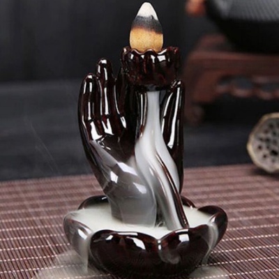 Incensário em cerâmica vidrada preta e branca em forma de mãos com fumo de incenso descendo