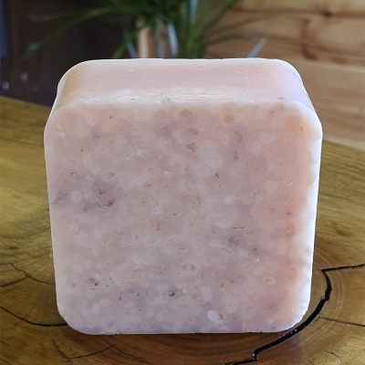 Sabonete quadrado rosa claro com textura granulada sobre madeira