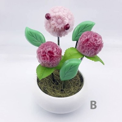 Arranjo floral cor-de-rosa em vaso branco com folhas verdes e letra B cinzenta