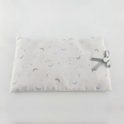 Almofada branca retangular com padrão de luas e pontos e fita cinzenta com coração