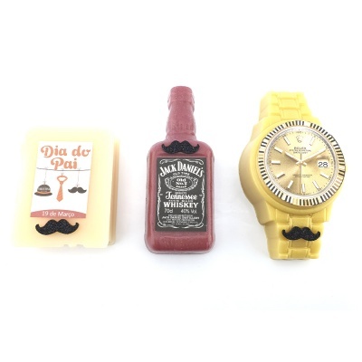 Três sabonetes coloridos: quadrado branco com etiqueta Dia do Pai, garrafa vermelha Jack Daniel's e relógio amarelo com bigode