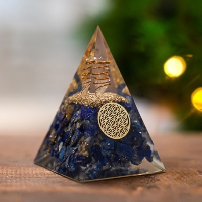 Pirâmide de resina transparente com pedras azuis e detalhes dourados em fundo desfocado