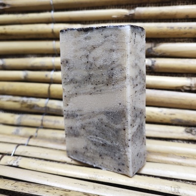 Sabonete artesanal retangular bege e cinza sobre bambu