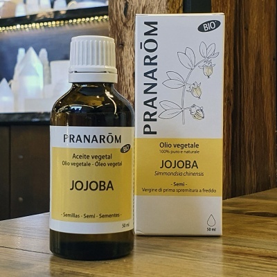 Frasco e embalagem de óleo vegetal de jojoba Pranarôm sobre mesa de madeira