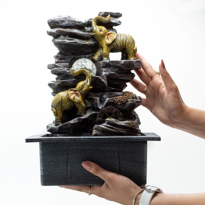 Fonte decorativa com elefantes dourados e rochas cinzentas