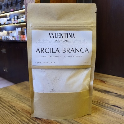 Embalagem de papel castanho com rótulo branco de Argila Branca da Valentina Body Care sobre mesa de madeira.