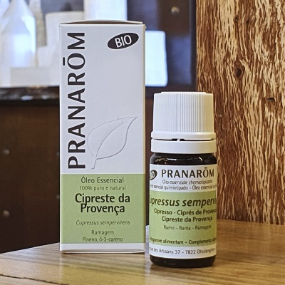 Frasco e caixa de óleo essencial Cipreste da Provença Pranarôm sobre mesa de madeira