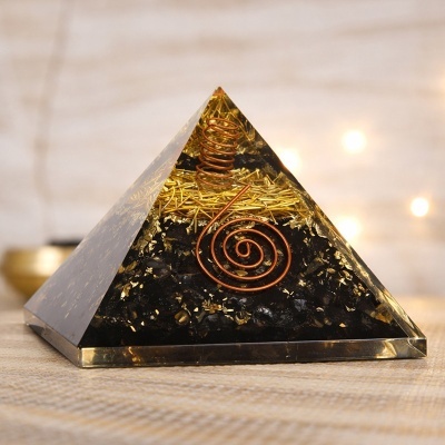 Pirâmide decorativa em resina com espiral de cobre e inclusões douradas e pretas.