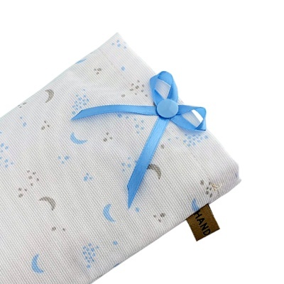 Lençol branco com padrão de luas e estrelas azuis e cinzentas, laço azul e etiqueta HAND