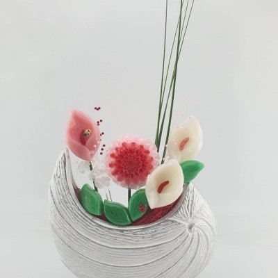 Arranjo floral decorativo com flores rosas, brancas e folhas verdes em base branca texturada