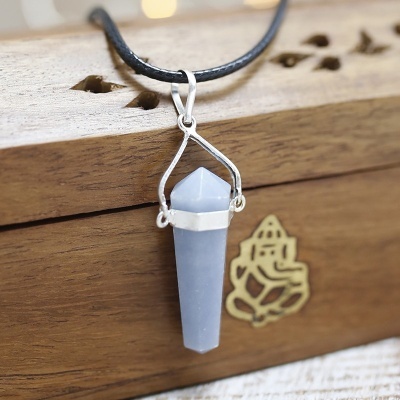 Colar com pendente de cristal azul claro em caixa de madeira com símbolo dourado.