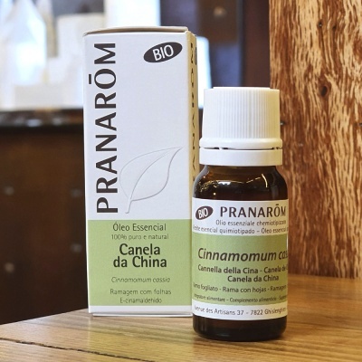 Frasco e caixa de óleo essencial Canela da China PRANARÔM BIO sobre superfície de madeira