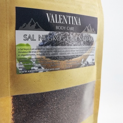 Embalagem amarela com sal negro visível e rótulo preto com texto em português.