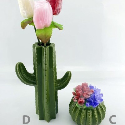 Vasos de cerâmica verde em forma de cacto com flores artificiais coloridas em fundo branco