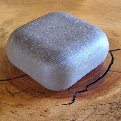 Sabonete quadrado translúcido sobre mesa de madeira clara