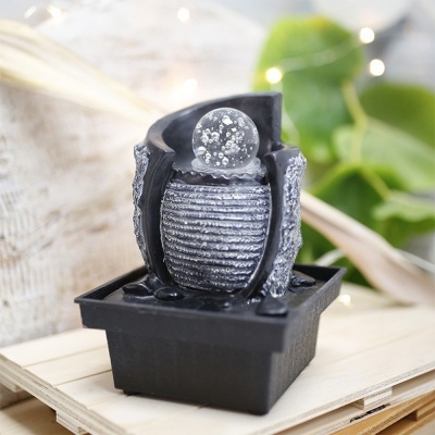 Fonte decorativa de mesa preta com esfera de vidro cheia de bolhas.