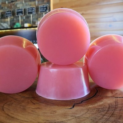 Sabonetes redondos cor de rosa sobre madeira com fundo de prateleira e parede de madeira