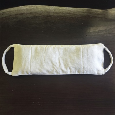 Máscara facial branca de tecido com alças sobre mesa escura