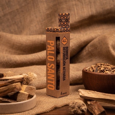 Embalagem de Palo Santo com paus de madeira e pedaços de madeira ao redor sobre tecido castanho