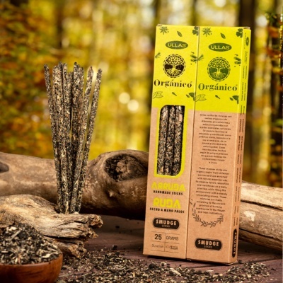 Pacote amarelo e castanho de incenso artesanal ULLAS Orgánico com sticks pretos ao lado em cenário rústico