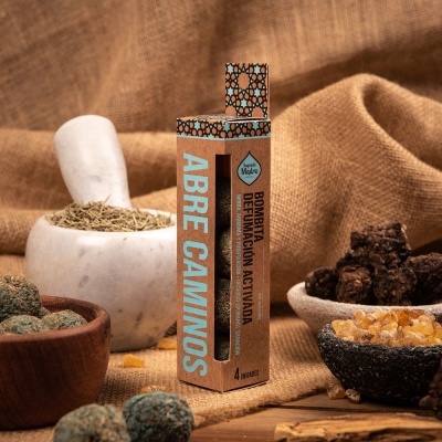 Embalagem de bombitas Abre Caminos em ambiente rústico com ervas e resinas