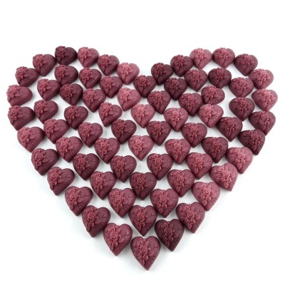 Bombons de chocolate em forma de coração com relevo floral, dispostos em coração grande