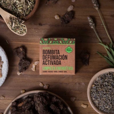 Caixa de bombitas de defumação ativa junto a ervas e resina sobre mesa de madeira