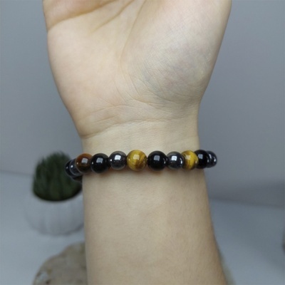 Pulseira de contas pretas, castanhas e amarelas em pulso