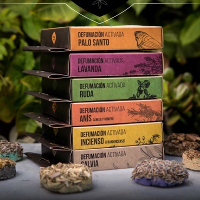 Caixas coloridas de incenso empilhadas com textos em espanhol e décor com flores secas