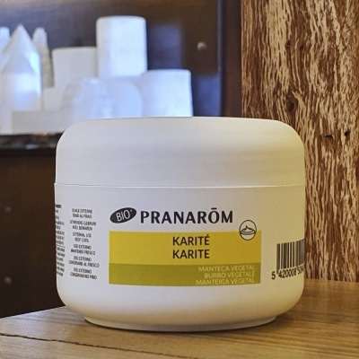 Pote branco de manteiga vegetal Pranarôm Karité numa superfície de madeira