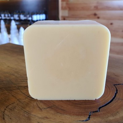 Sabonete quadrado creme sobre mesa de madeira rústica com fundo desfocado de interior