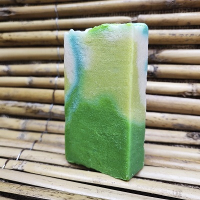 Barra de sabão colorida em verde, amarelo e azul sobre bambu