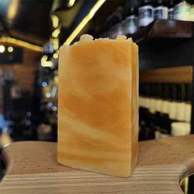 Sabonete amarelo marmorizado em tábua de madeira com prateleiras ao fundo