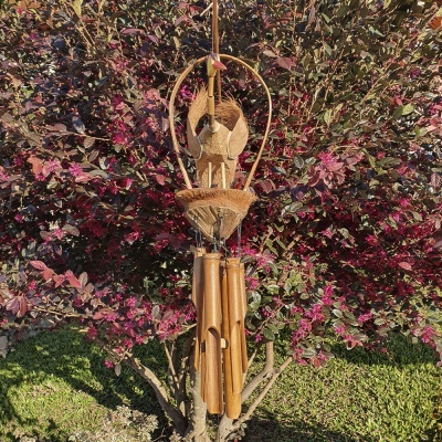 Sino dos ventos de madeira pendurado em árvore com folhas vermelhas e verdes