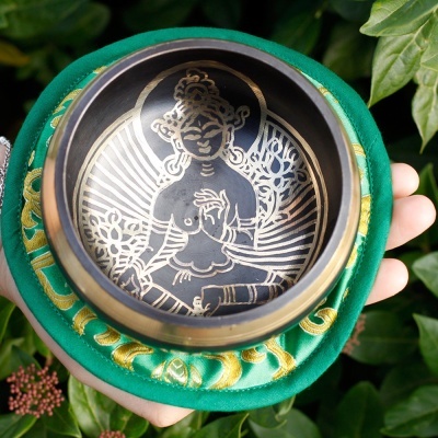 Tigela metálica com figura gravada e almofada verde ornamental