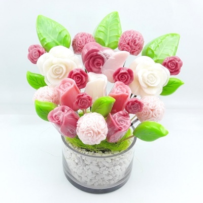 Arranjo de flores artificiais rosa, branco e verde em vaso transparente com pedras brancas
