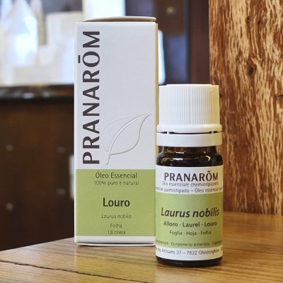 Frasco de óleo essencial Pranarôm Louro com caixa sobre mesa de madeira