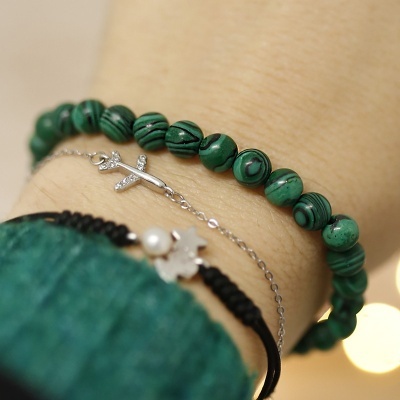 Pulseira de contas verdes, corrente com crucifixo e pulseira preta no pulso