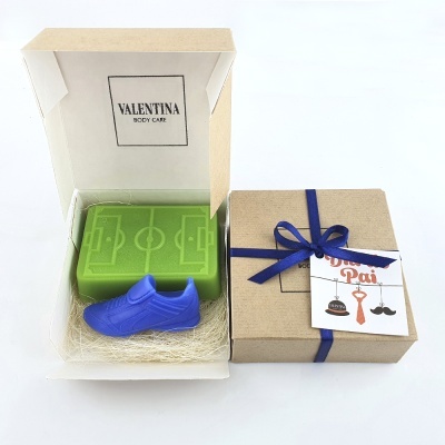 Caixa de presente com sabão em forma de chuteira e barra com desenho de campo de futebol