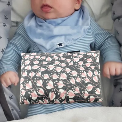 Mala floral cinza e rosa sobre bebé vestido azul com babete azul claro