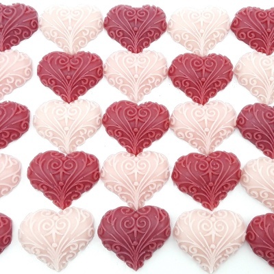 Chocolates em forma de coração com padrões decorativos em rosa claro e vermelho