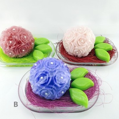 Sabonetes decorativos em forma de rosas coloridas com sabonetes verdes em forma de folhas em pratos transparentes.