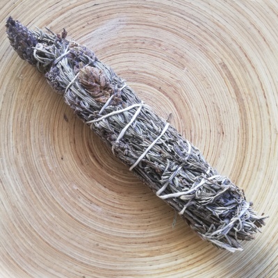 Vara de ervas secas amarradas com cordão branco sobre madeira clara