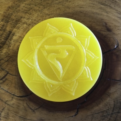 Disco redondo amarelo com símbolo em relevo sobre madeira