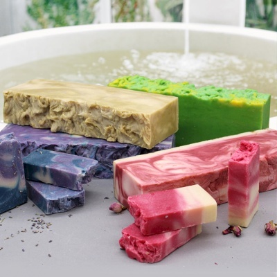 Sabonetes artesanais coloridos com texturas variadas sobre superfície cinzenta