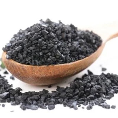 Concha de madeira com grãos pretos de carvão ativado em fundo branco