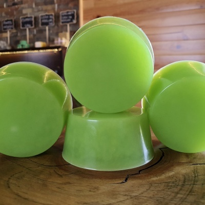 Três bolas verdes translúcidas e suporte verde sobre mesa de madeira