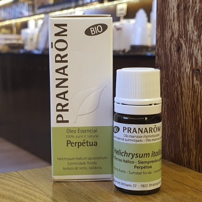 Frasco e caixa do óleo essencial Helichrysum italicum PRANARÔM sobre superfície de madeira