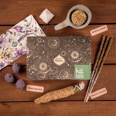 Kit de limpeza energética com caixa decorada, varas de incenso, flor seca, trigramas com texto e envelope floral sobre fundo de madeira