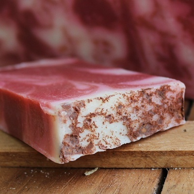 Barra de sabão artesanal marmoreada em rosa, branco e castanho sobre madeira